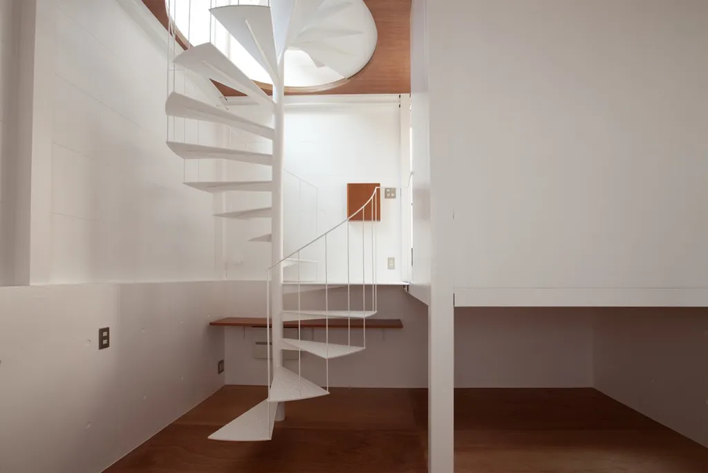 Cầu thang xoắn với thiết kế bằng thép được sơn tĩnh điện màu trắng mang lại sự tối giản và tinh tế, được đặt trong một không gian nhỏ với các bậc thang dạng mở.