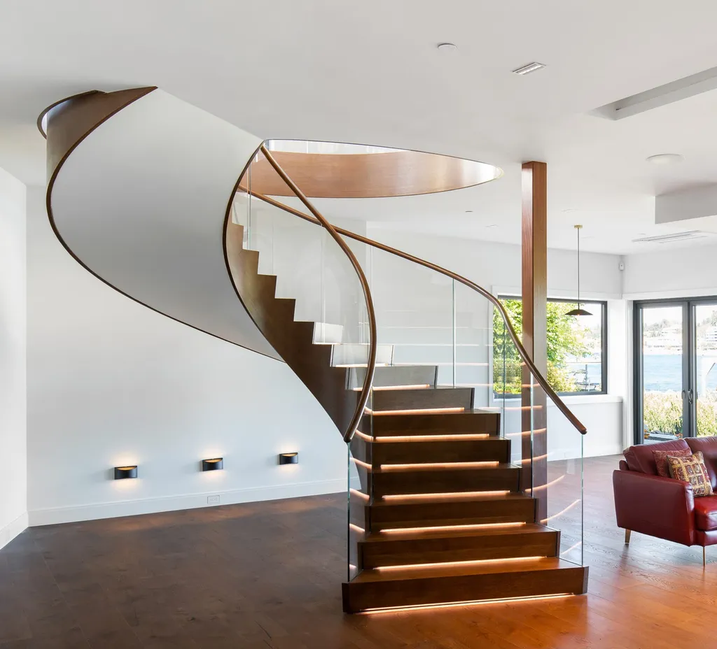 Mẫu cầu thang hiện đại với lan can bằng kính và những bậc thang bằng gỗ có đèn chiếu sáng.