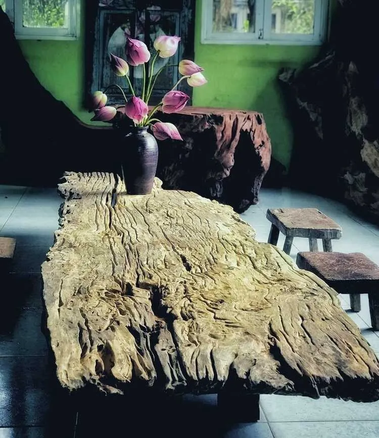 Tấm gỗ lũa lớn làm mặt bàn mang lại nét mộc mạc bình dị thuần Việt cho không gian, nhắc nhở con người về những giá trị sống đi cùng năm tháng