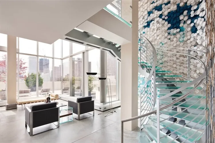 Cầu thang xoắn ốc với mặt bậc bằng kính mờ và lan can kim loại, tăng sự chắc chắn, kết hợp với hiệu ứng trang trí tường tạo nên sự tinh tế, độc đáo.