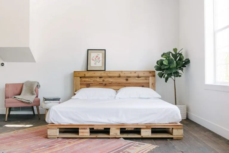 Phòng ngủ phong cách Hàn Quốc với những trang trí rất đơn giản: chiếc giường từ các tấm pallet, chiếc ghế sofa đơn hồng và cây cảnh đầu giường