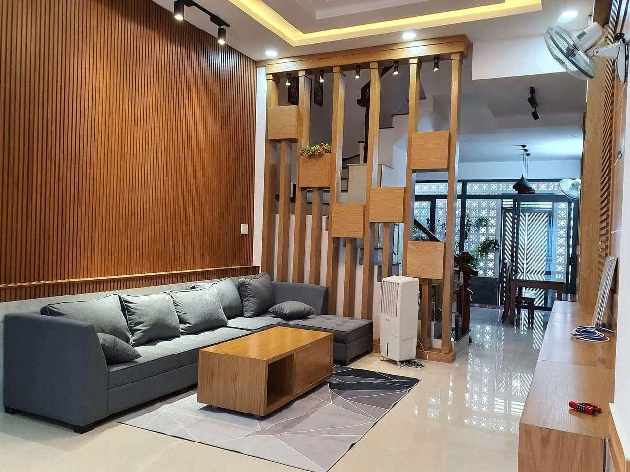 Phòng khách nhà ống 4m với ốp vách lam gỗ và bộ ghế sofa màu trầm, mang đến một không gian vừa đơn giản, vừa tinh tế