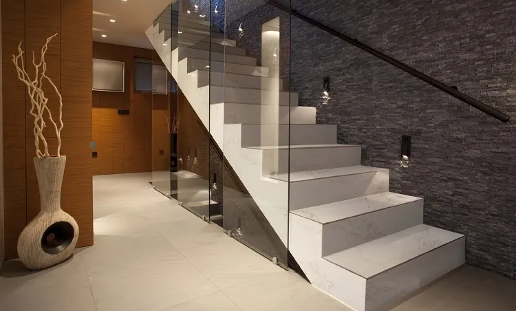 Sử dụng đá ốp cả trên bậc cầu thang và cạnh bên phối hợp với lan can kính càng làm tăng thêm sự sang trọng cho không gian. 