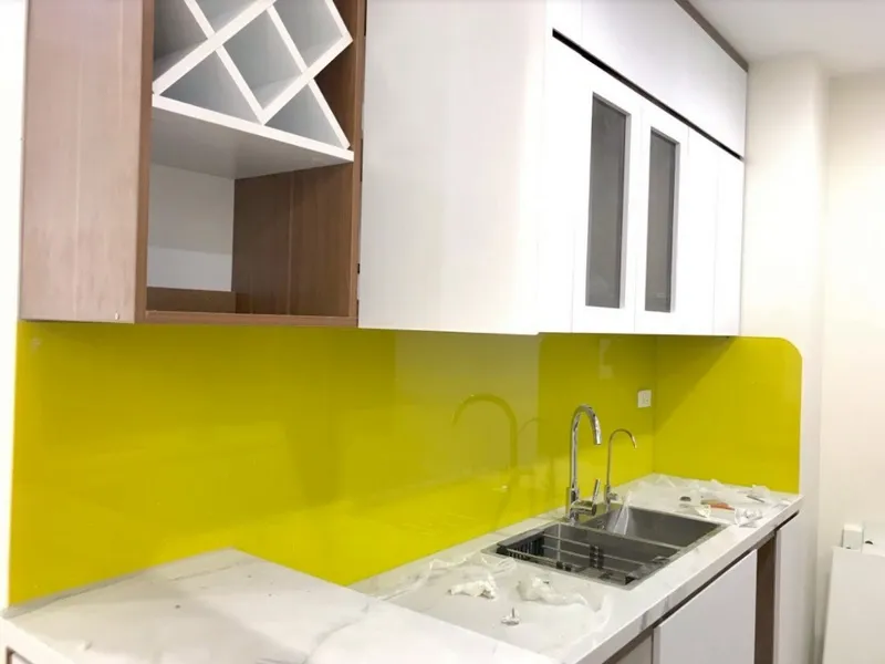 Kính ốp bếp trơn màu xanh vàng kết hợp với màu trắng của nội thất nhà bếp vô cùng nổi bật
