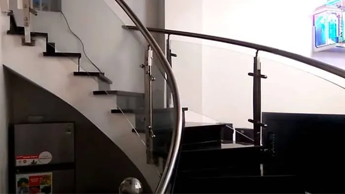Cầu thang inox xoắn ốc có bậc thang đá màu đen và tay vịn inox phối kính cường lực